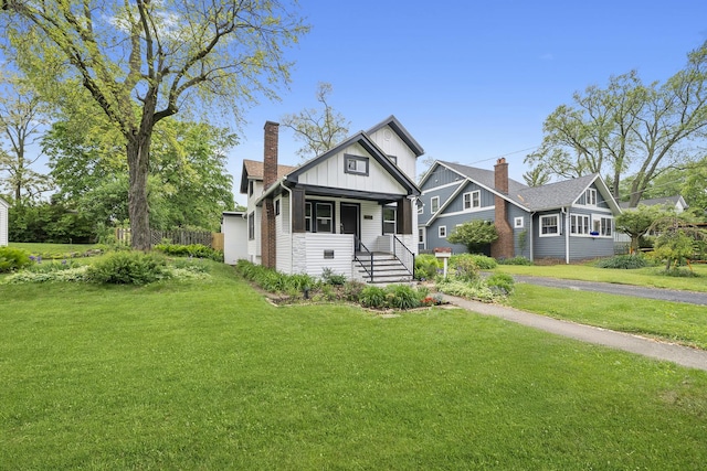 504 Newton Ave, Glen Ellyn, IL 60137 - view of front of house featuring board and batten siding, a front lawn, covered porch, and a chimney