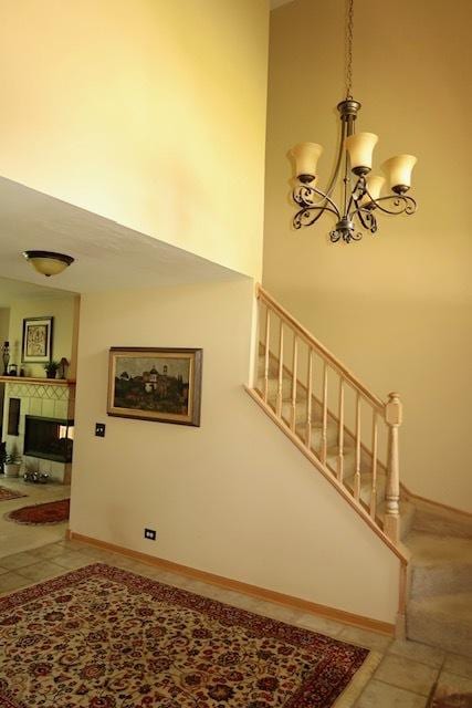 957 Chancery Ln, Cary, IL 60013 - stairway with a chandelier, a tile fireplace, tile patterned flooring, baseboards, and a high ceiling