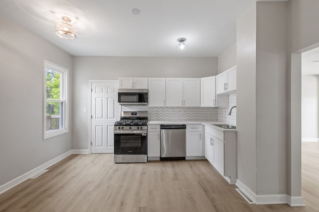 1729 S Hamilton St, Lockport, IL 60441 - kitchen featuring stainless steel appliances, a sink, tasteful backsplash, light wood finished floors, and white cabinetry