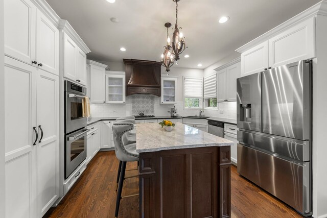 1728 Elyse Ln, Naperville, IL 60565 - kitchen with appliances with stainless steel finishes, custom range hood, dark wood finished floors, a kitchen island, and glass insert cabinets