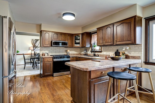 1402 Winaki Trl, Algonquin, IL 60102 - kitchen featuring stainless steel appliances, a sink, a peninsula, wood finished floors, and decorative backsplash