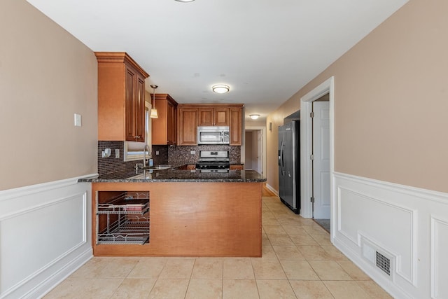 7817 Menard Ave, Burbank, IL 60459 - kitchen featuring stainless steel appliances, a peninsula, wainscoting, dark stone counters, and brown cabinetry