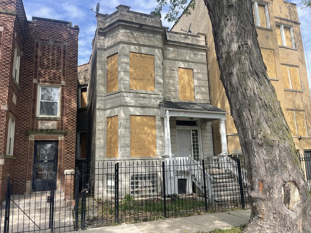 636 N St Louis Ave, Chicago, IL 60624 - view of front facade with stone siding and a fenced front yard
