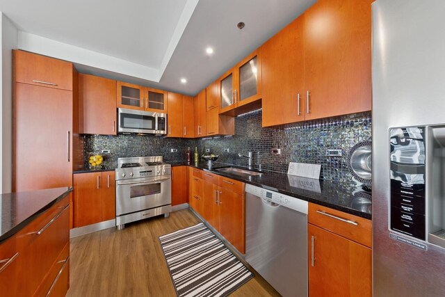 1250 S Indiana Ave Unit 1301, Chicago, IL 60605 - kitchen with stainless steel appliances, a sink, light wood-style floors, tasteful backsplash, and brown cabinets