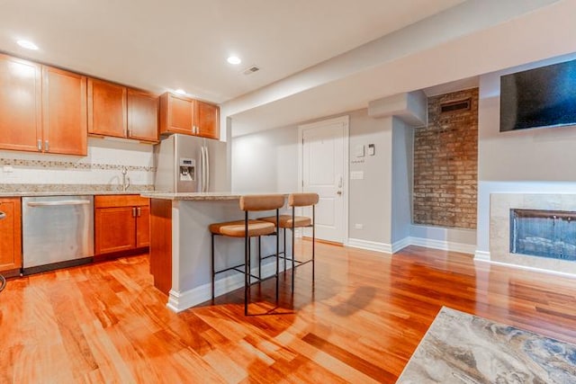 4111 N Kenmore Ave Unit 1Ng, Chicago, IL 60613 - kitchen with appliances with stainless steel finishes, light wood-style flooring, a breakfast bar area, light countertops, and a kitchen island
