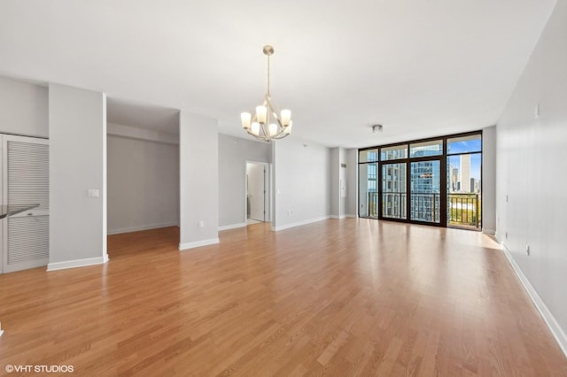 233 E 13th St Unit 1902, Chicago, IL 60605 - unfurnished living room featuring a chandelier, a wall of windows, light wood-style floors, and baseboards