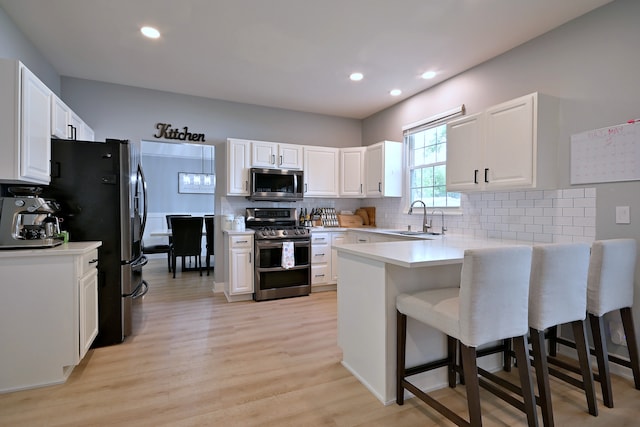 1422 Deer Creek Ln, Lake In The Hills, IL 60156 - kitchen with stainless steel appliances, a sink, a peninsula, light wood-style flooring, and a kitchen bar