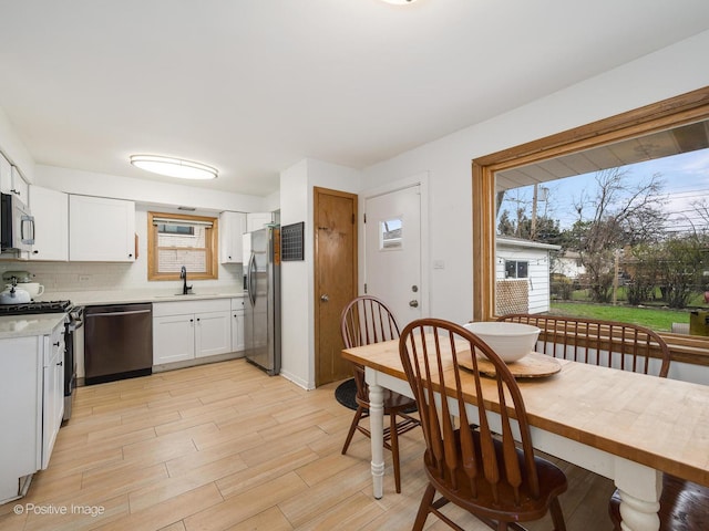 4048 W 105th St, Oak Lawn, IL 60453 - kitchen featuring stainless steel appliances, light countertops, backsplash, white cabinetry, and light wood-style flooring