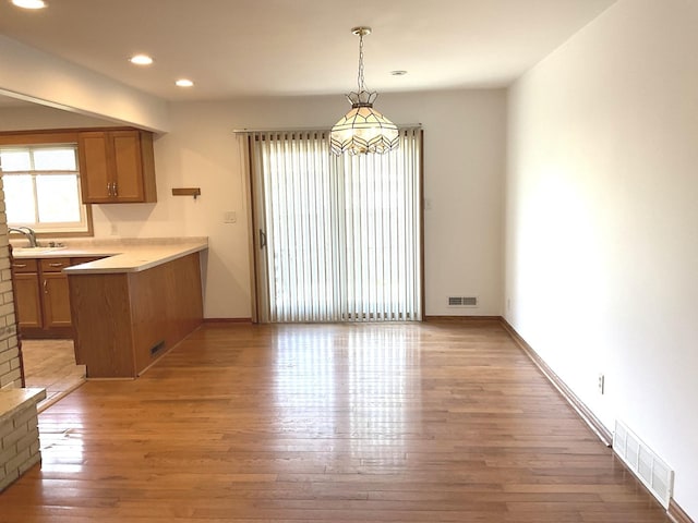 813 Junie Ct, Joliet, IL 60435 - kitchen with brown cabinetry, a peninsula, light wood-type flooring, pendant lighting, and recessed lighting