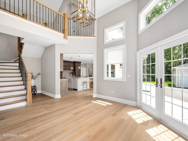 608 W 55th St, Hinsdale, IL 60521 - unfurnished living room featuring a towering ceiling, light wood-type flooring, baseboards, stairs, and a chandelier