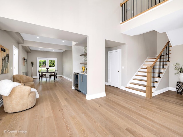 608 W 55th St, Hinsdale, IL 60521 - living room featuring wine cooler, a bar, stairway, light wood-style flooring, and baseboards