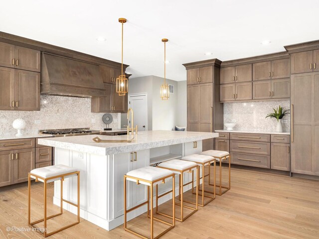 608 W 55th St, Hinsdale, IL 60521 - kitchen with custom exhaust hood, backsplash, light countertops, a kitchen breakfast bar, and light wood finished floors