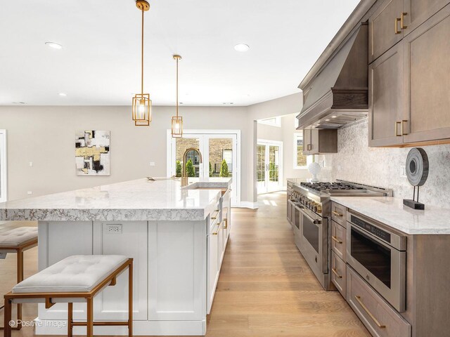 608 W 55th St, Hinsdale, IL 60521 - kitchen with range with two ovens, light wood-type flooring, a sink, decorative backsplash, and premium range hood