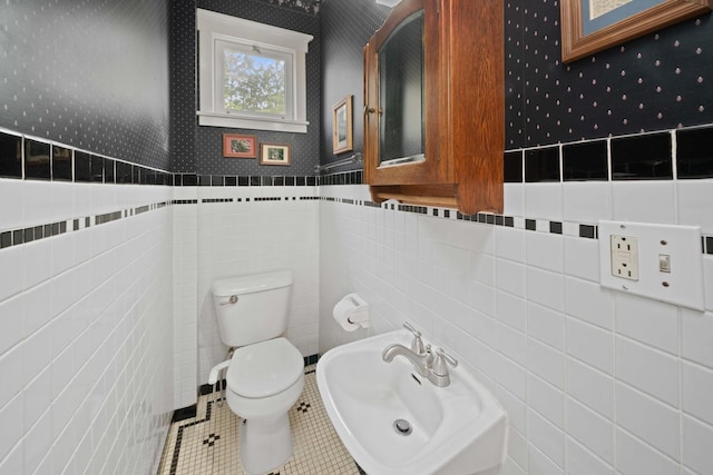119 E 4th St, Sandwich, IL 60548 - bathroom with tile walls, toilet, a sink, wallpapered walls, and tile patterned floors