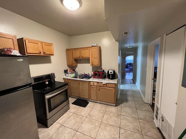 801 S Kedvale Ave, Chicago, IL 60624 - kitchen featuring appliances with stainless steel finishes, a sink, light tile patterned floors, light countertops, and brown cabinets