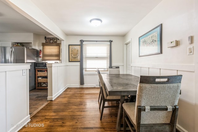 dining area featuring wood finished floors, a wainscoted wall, and a decorative wall
