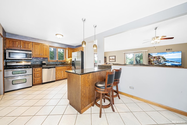13443 S Forest Ln, Lockport, IL 60441 - kitchen with stainless steel appliances, brown cabinetry, a peninsula, a breakfast bar, and light tile patterned flooring