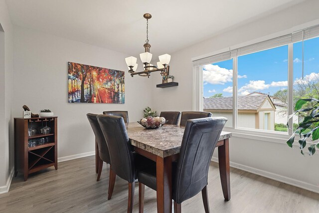 228 Oriole Rd, Matteson, IL 60443 - dining room featuring a chandelier, light wood finished floors, baseboards, and healthy amount of natural light