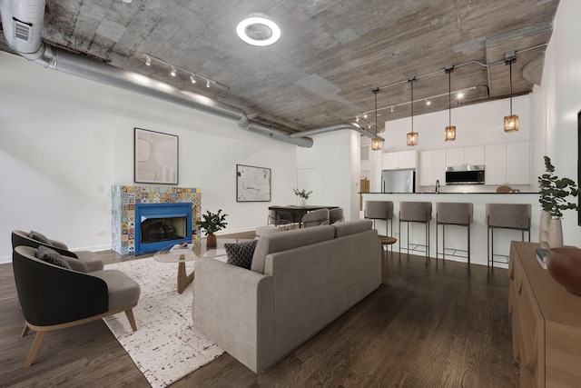 1110 W 15th St Unit 114, Chicago, IL 60608 - living room featuring dark wood-type flooring, rail lighting, a towering ceiling, a tiled fireplace, and baseboards