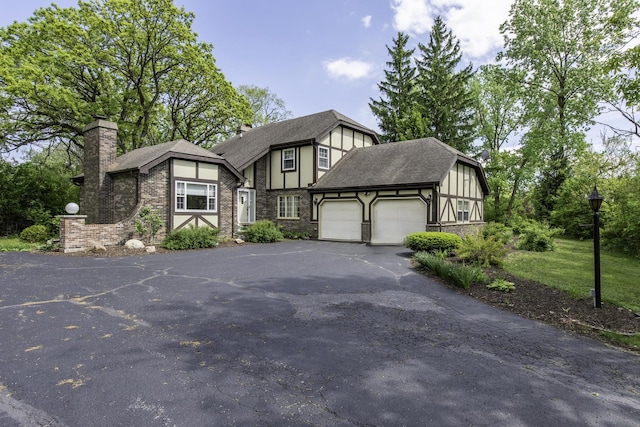 12375 W Ash Ct, Beach Park, IL 60099 - english style home with a garage, asphalt driveway, a chimney, a shingled roof, and stone siding