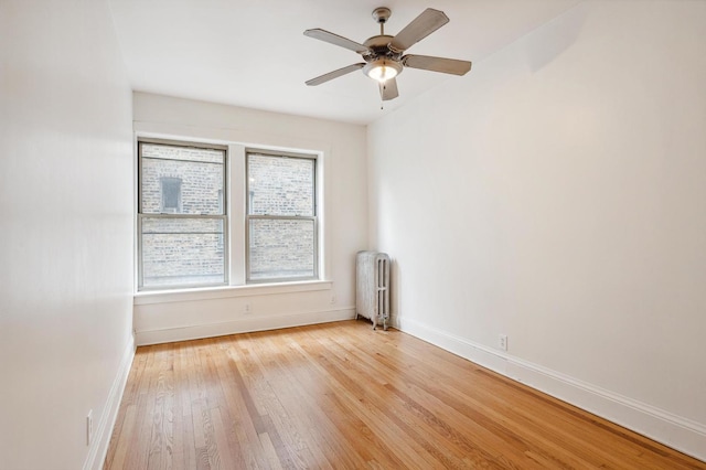 5452 S Cornell Ave Unit 1E, Chicago, IL 60615 - spare room featuring radiator heating unit, baseboards, light wood finished floors, and a ceiling fan