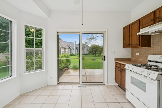 611 Kingsbridge Dr, Carol Stream, IL 60188 - kitchen with white gas stove, under cabinet range hood, plenty of natural light, and decorative backsplash