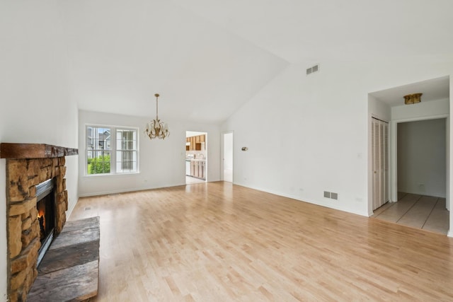 611 Kingsbridge Dr, Carol Stream, IL 60188 - unfurnished living room with a chandelier, a stone fireplace, light wood-type flooring, and high vaulted ceiling