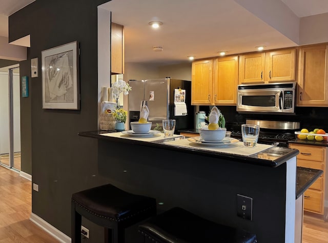 828 Graceland Ave Unit 404, Des Plaines, IL 60016 - kitchen featuring stainless steel appliances, dark countertops, light wood-style floors, baseboards, and light brown cabinetry