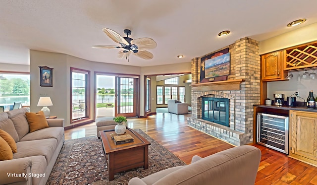 2903 Prairie Meadow Dr, Champaign, IL 61822 - living area with wine cooler, wood finished floors, a ceiling fan, bar, and a brick fireplace