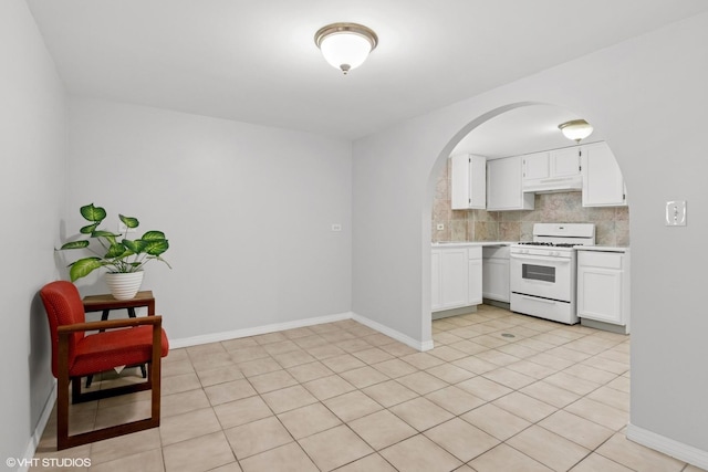5200 S Mozart Ave, Chicago, IL 60632 - kitchen featuring white gas stove, arched walkways, light countertops, under cabinet range hood, and white cabinetry