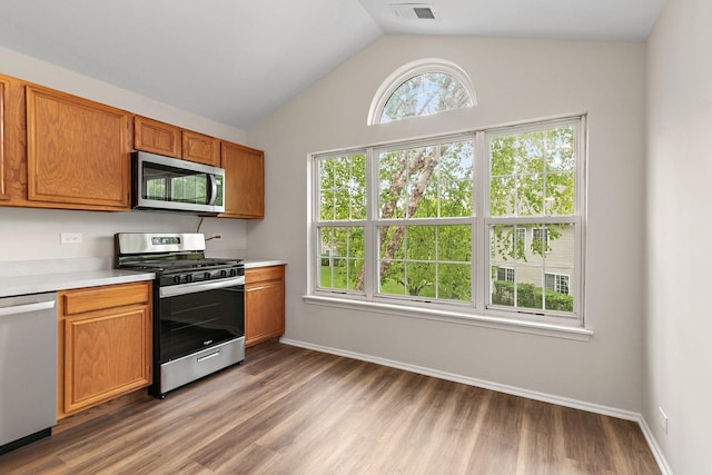 1623 Camberley Ct, Bartlett, IL 60103 - kitchen with stainless steel appliances, light countertops, wood finished floors, vaulted ceiling, and brown cabinetry