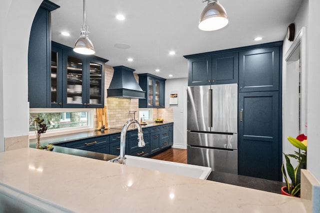 2906 Lincoln St, Evanston, IL 60201 - kitchen featuring stainless steel refrigerator, custom range hood, blue cabinets, a sink, and tasteful backsplash