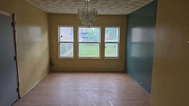 316 E 107th St, Chicago, IL 60628 - unfurnished dining area featuring a chandelier, baseboards, wood finished floors, and a textured ceiling