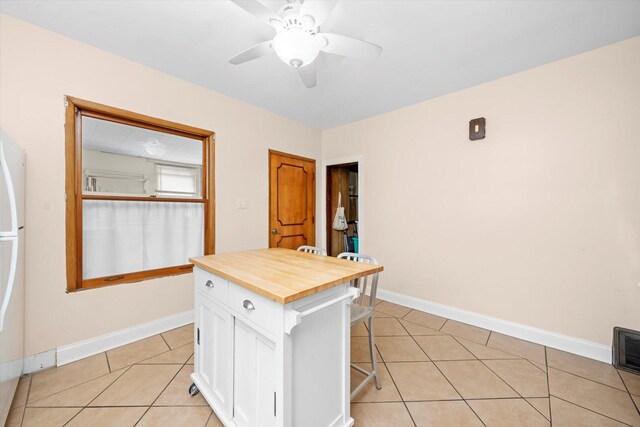 6141 W Peterson Ave, Chicago, IL 60646 - kitchen featuring wooden counters, white cabinets, light tile patterned floors, and a kitchen breakfast bar