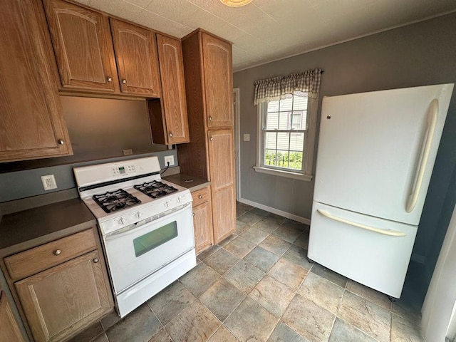 826 N 11th St, Rochelle, IL 61068 - kitchen with white appliances, stone tile floors, dark countertops, baseboards, and brown cabinets