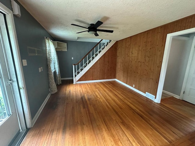 826 N 11th St, Rochelle, IL 61068 - unfurnished living room with baseboards, wood-type flooring, wood walls, a textured ceiling, and a ceiling fan