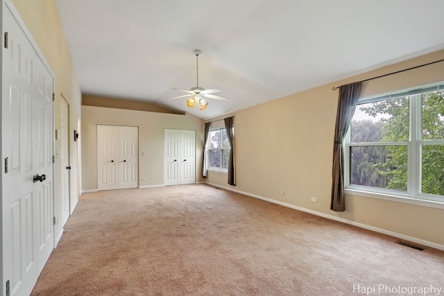 996 Highgate Ln, Grayslake, IL 60030 - unfurnished bedroom featuring multiple windows, light colored carpet, two closets, lofted ceiling, and a ceiling fan