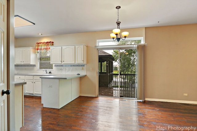 996 Highgate Ln, Grayslake, IL 60030 - kitchen featuring a peninsula, white cabinetry, decorative light fixtures, dark wood-type flooring, and decorative backsplash