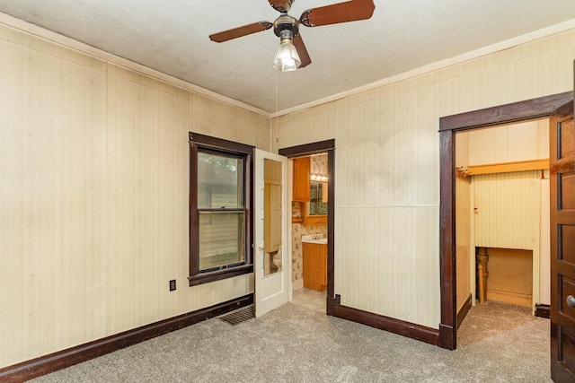 909 Woods Ave, Joliet, IL 60436 - unfurnished bedroom featuring carpet, baseboards, crown molding, a spacious closet, and a ceiling fan