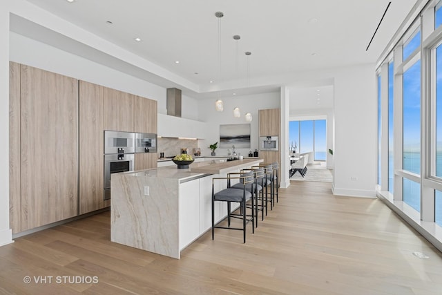 363 E Wacker Dr Unit 7501, Chicago, IL 60601 - kitchen featuring modern cabinets, light wood-type flooring, a spacious island, a kitchen breakfast bar, and plenty of natural light