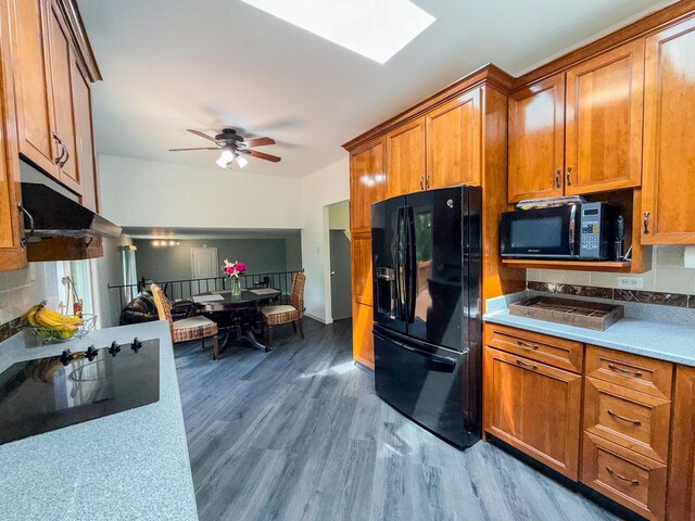 12533 S Iroquois Rd, Palos Park, IL 60464 - kitchen with black appliances, brown cabinetry, wood finished floors, a skylight, and light countertops