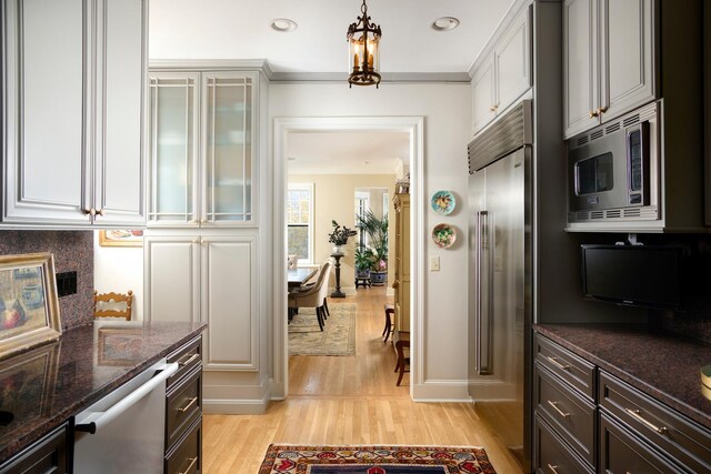 635 W Sheridan Rd Unit 3, Chicago, IL 60613 - kitchen featuring appliances with stainless steel finishes, light wood-style floors, ornamental molding, dark stone countertops, and decorative light fixtures
