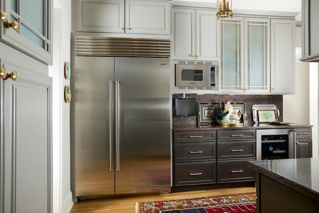 635 W Sheridan Rd Unit 3, Chicago, IL 60613 - kitchen featuring built in appliances, wine cooler, dark stone counters, light wood finished floors, and white cabinets
