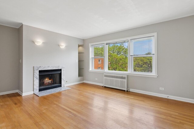 524 Michigan Ave Unit 3N, Evanston, IL 60202 - unfurnished living room with radiator heating unit, light wood-style flooring, a high end fireplace, baseboards, and crown molding