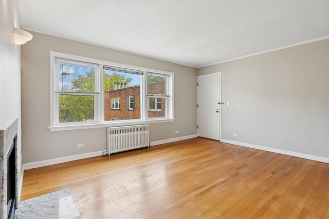 524 Michigan Ave Unit 3N, Evanston, IL 60202 - unfurnished living room featuring radiator, light wood-style floors, baseboards, a brick fireplace, and crown molding