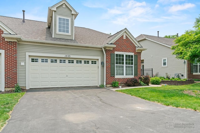 1553 Catalina Ln, Aurora, IL 60504 - view of front facade featuring driveway, brick siding, an attached garage, and roof with shingles