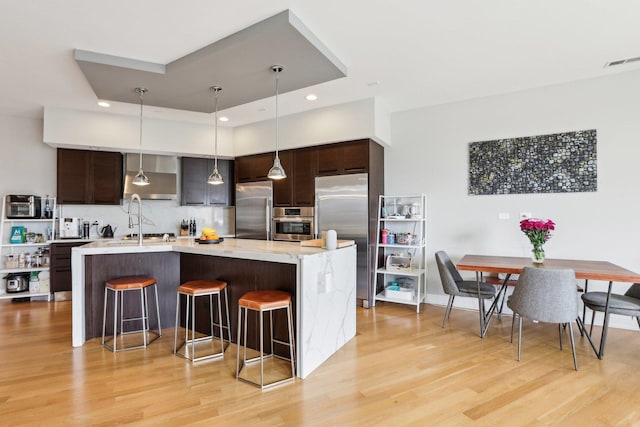 650 N Morgan St Unit 303, Chicago, IL 60642 - kitchen with stainless steel appliances, light wood-type flooring, a breakfast bar, dark brown cabinetry, and recessed lighting
