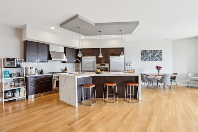 650 N Morgan St Unit 303, Chicago, IL 60642 - kitchen with wall chimney exhaust hood, stainless steel appliances, a sink, light wood-style floors, and recessed lighting