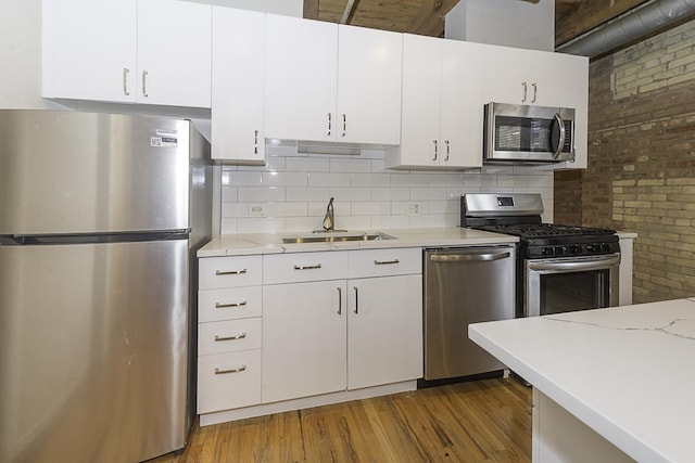 420 S Clinton St Unit 408A, Chicago, IL 60607 - kitchen featuring stainless steel appliances, wood finished floors, white cabinets, decorative backsplash, and brick wall