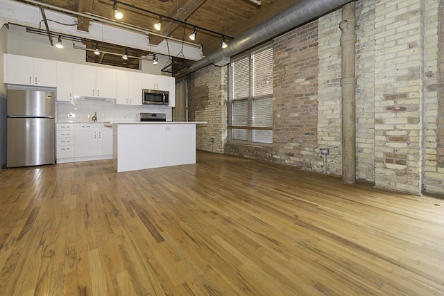 420 S Clinton St Unit 408A, Chicago, IL 60607 - kitchen with appliances with stainless steel finishes, brick wall, rail lighting, wood finished floors, and white cabinets